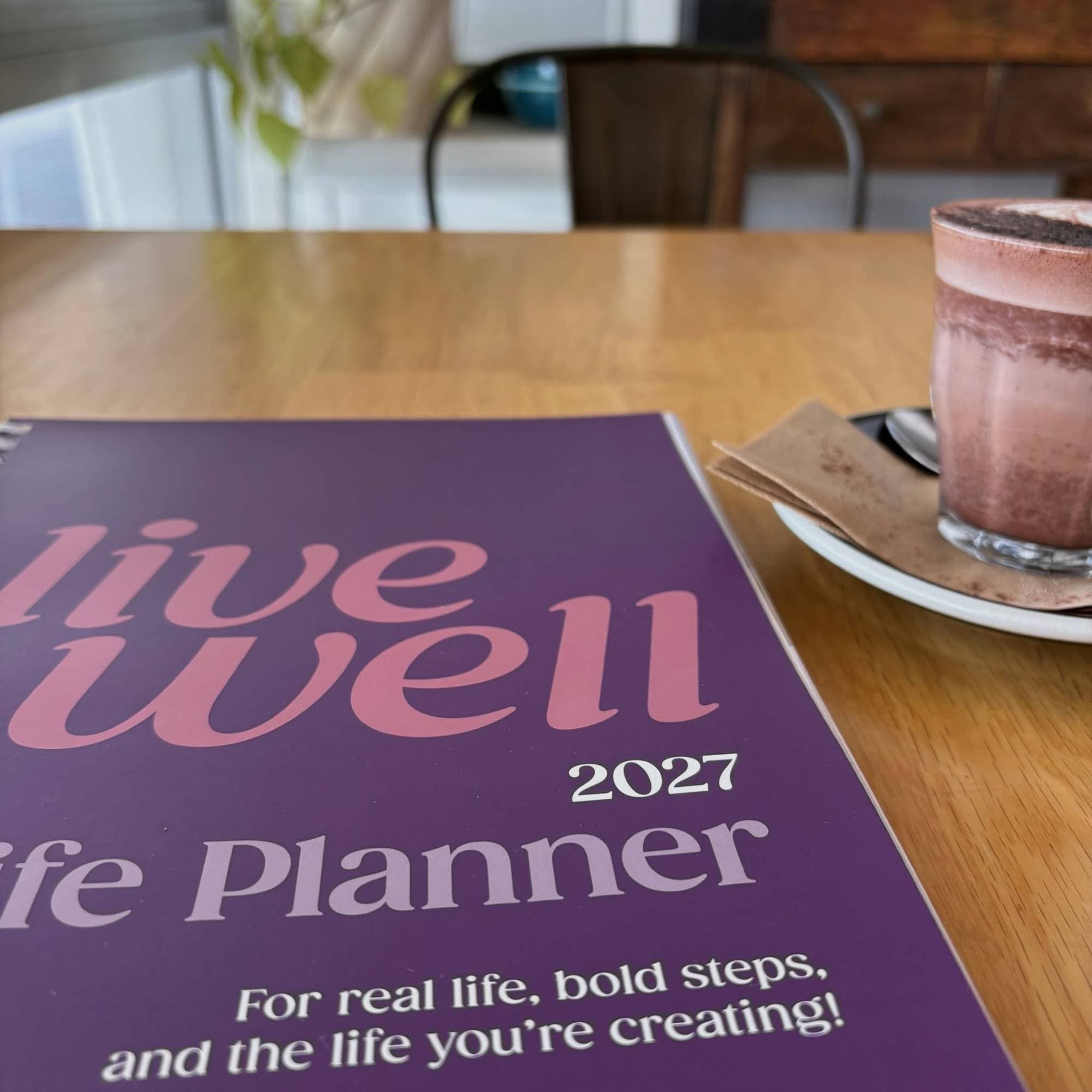 The Planner on a cafe table beside a hot chocolate
