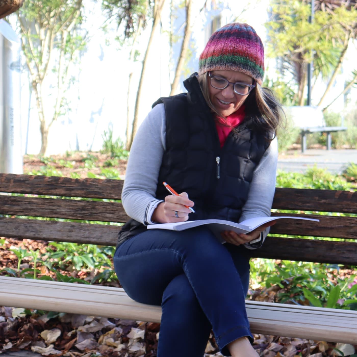 Tracey Hancock writing in the Live Well Life Planner on a park bench